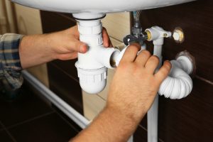 a plumber is reassembling a drain for clogged drain repair